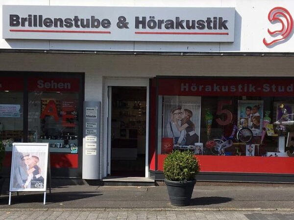 Fassade eines Fachgeschäfts für Brillen und Hörakustik mit Schaufenstern und Werbeplakat.