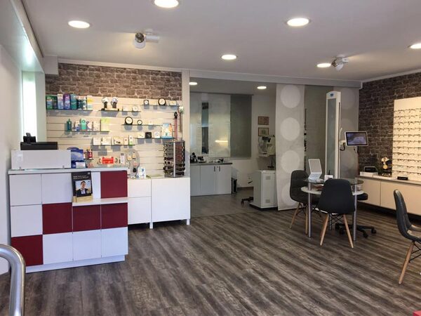 Modern eingerichtetes Optikerfachgeschäft mit Brillenregalen, Beratungstischen und Verkaufsfläche.